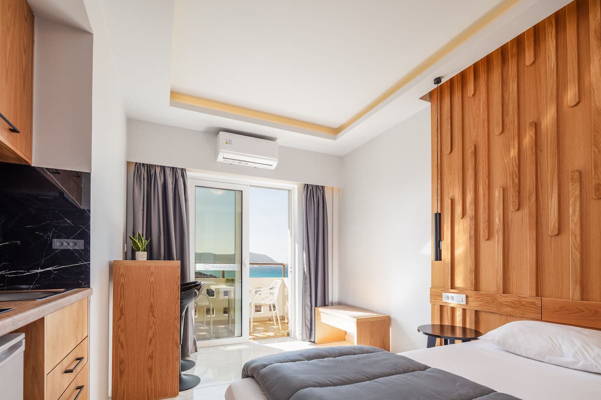 Une chambre d’hôtel moderne équipée d’un lit, d’un bureau, d’une télévision et d’un balcon avec vue sur la mer.