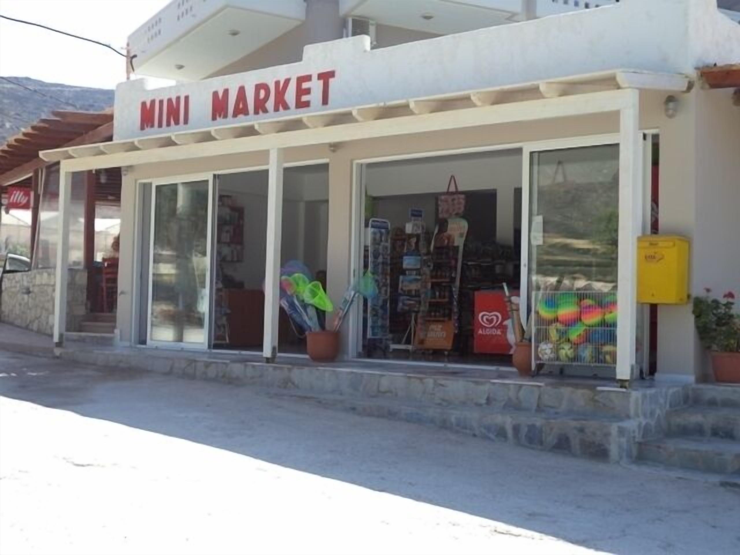 Un escaparate con un letrero que dice "MINI MARKET" y varios artículos exhibidos en el exterior.