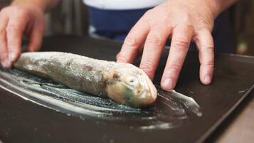 Une personne qui tient un poisson sur une planche à découper.