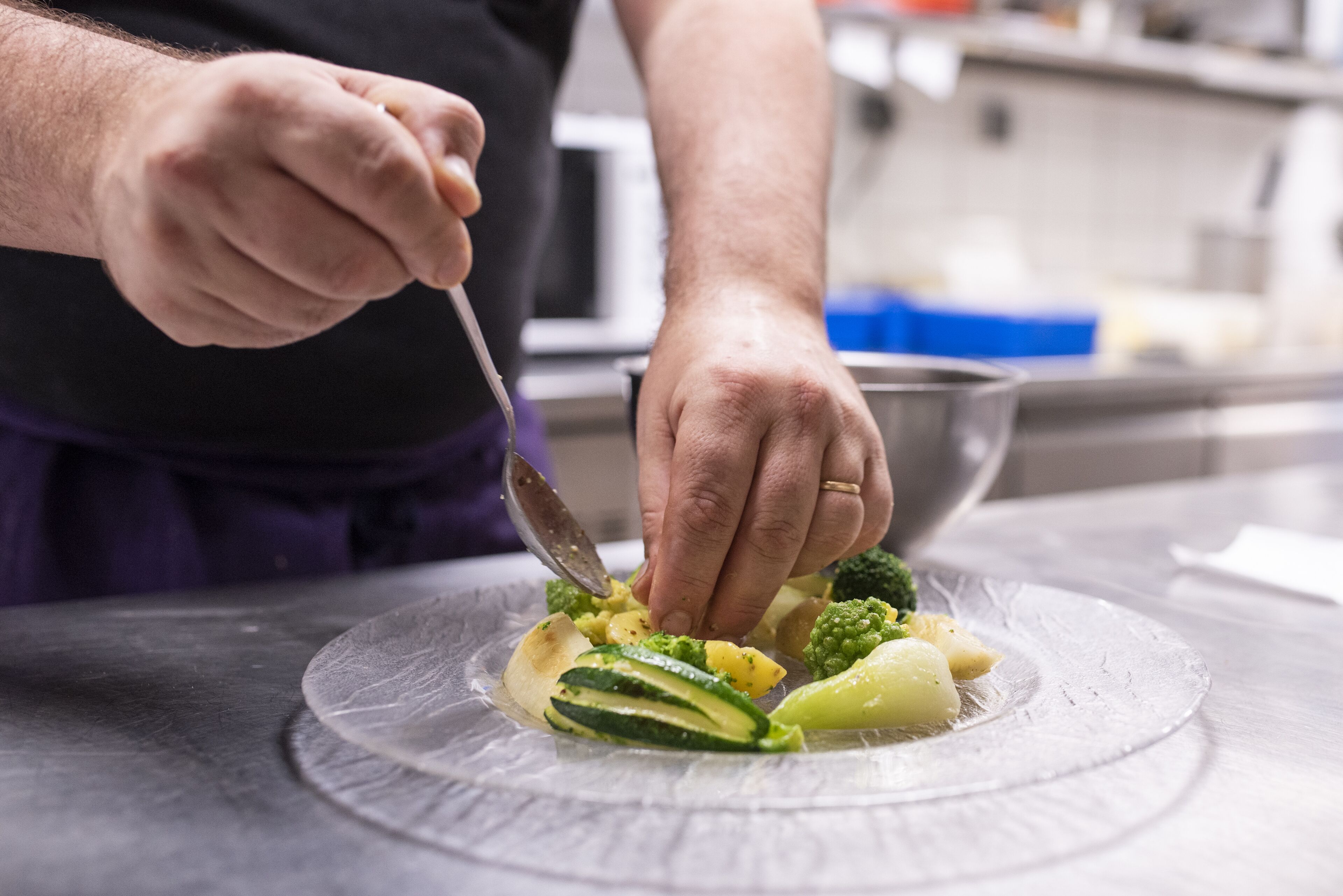Une personne prépare des aliments sur une assiette en verre transparent dans une cuisine.