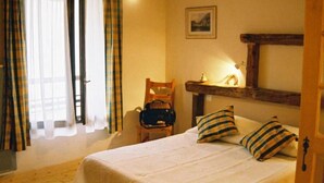 A bedroom with a bed, pillows, a chair, a wooden shelf, and a painting on the wall. - Auberge d'Anthy (Anthy-sur-Leman)