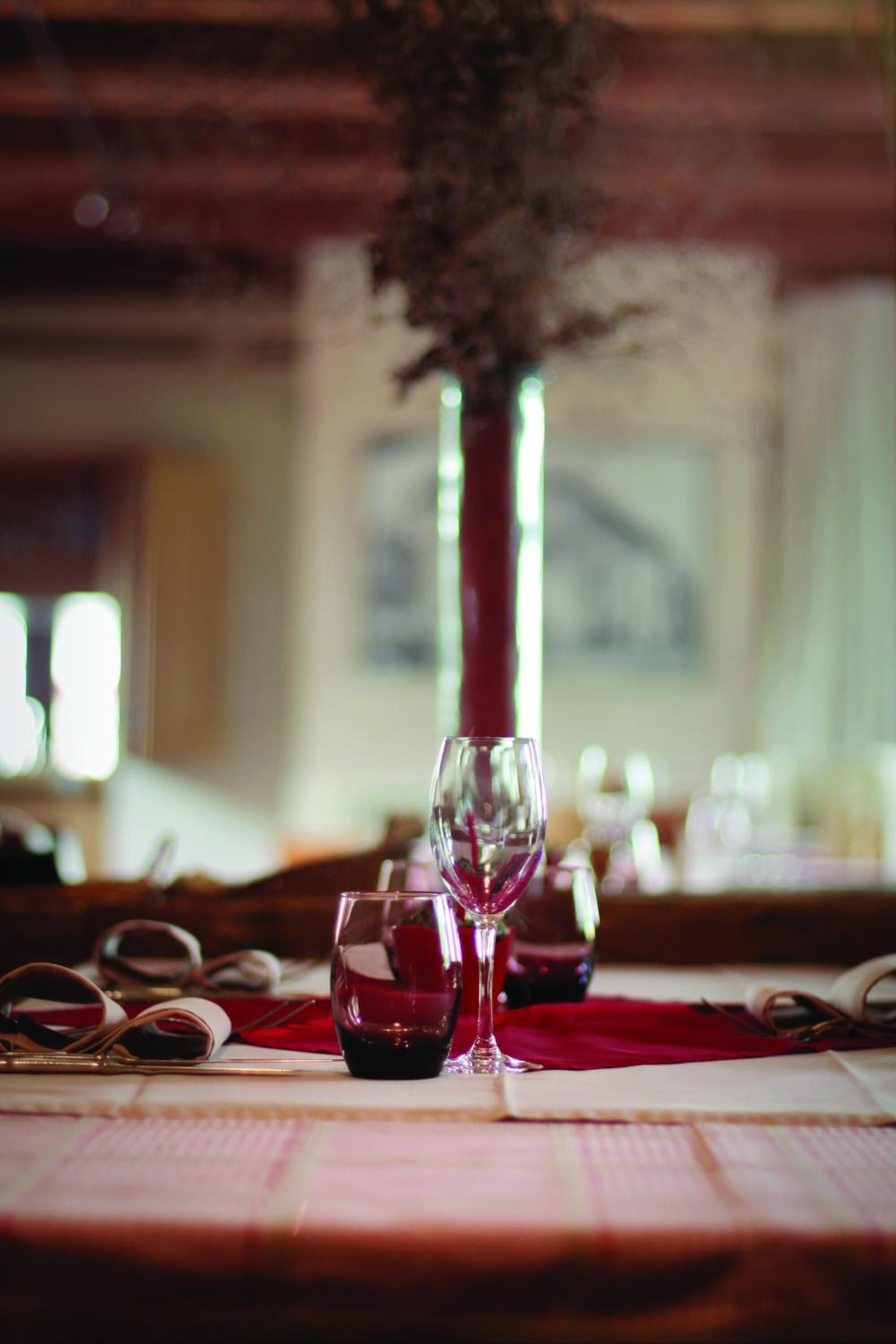 A table with a red cloth, a clear wine glass, and a book.