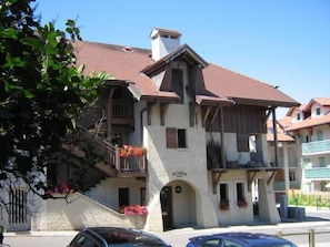 A traditional chalet-style building with a steeply pitched roof, a balcony with flower boxes, and a visible entrance.
