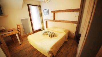Een slaapkamer met een houten bed, een bureau en een stoel.