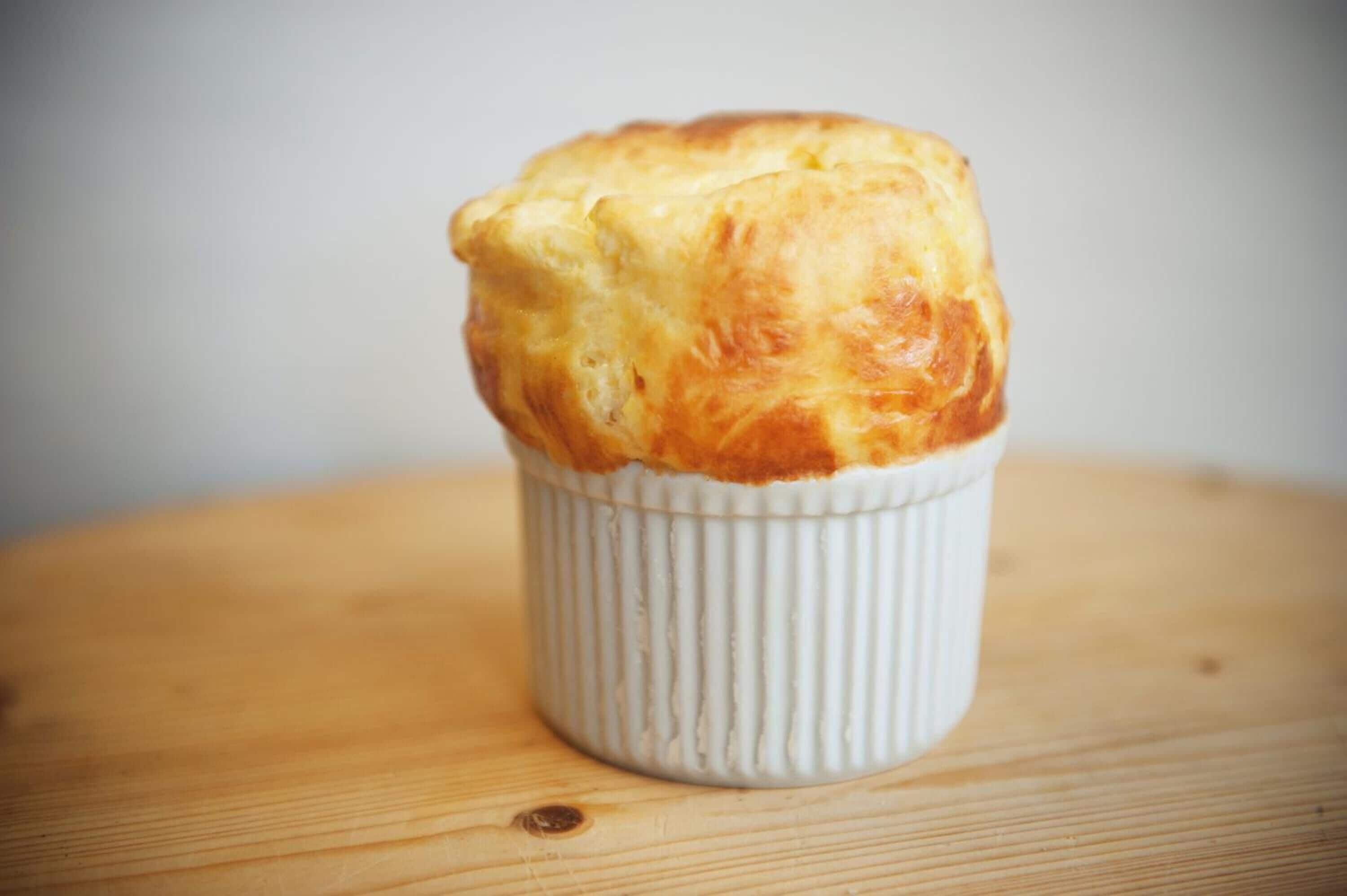 Un muffin en un recipiente blanco de cerámica sobre una superficie de madera.