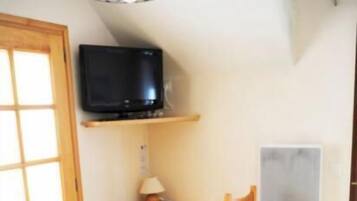 Een kamer met een bed, een bureau, een stoel, een televisie en een raam.