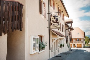 A building with a sign for 'L'Auberge d'Anthy Hotel Restaurant' with a balcony and potted plants.