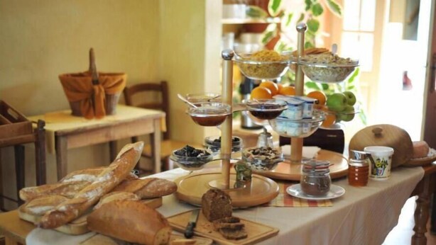 A table with various food items and bread, including baguettes and a tiered stand with bowls and jars. - Auberge d'Anthy (Anthy-sur-Leman)
