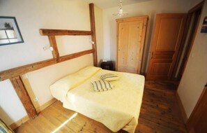 A room with a bed, wooden beams, a wardrobe, and a door.