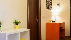A reception area with a white desk, a small orange desk, and two potted plants. - Le Coccole (Catania)