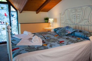 A bed with floral bedding, a bedside lamp, and towels. - Le Coccole (Catania)