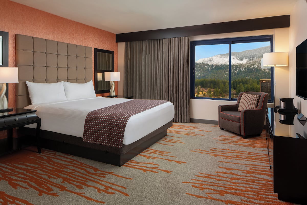 A hotel room with a large bed, a chair, a desk, and a TV.