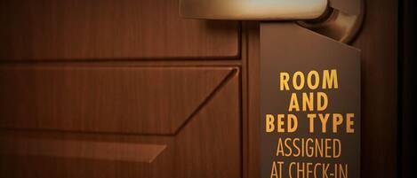 A wooden door with a sign indicating room and bed type assigned at check-in.