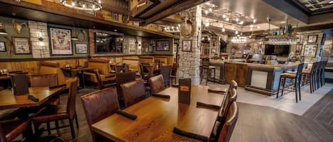 A restaurant with wooden tables and booths, stone accents, and a bar area.