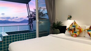 Ett sovrum med en stor säng, utsikt över havet och en balkong med blå kakelplattor på golvet.