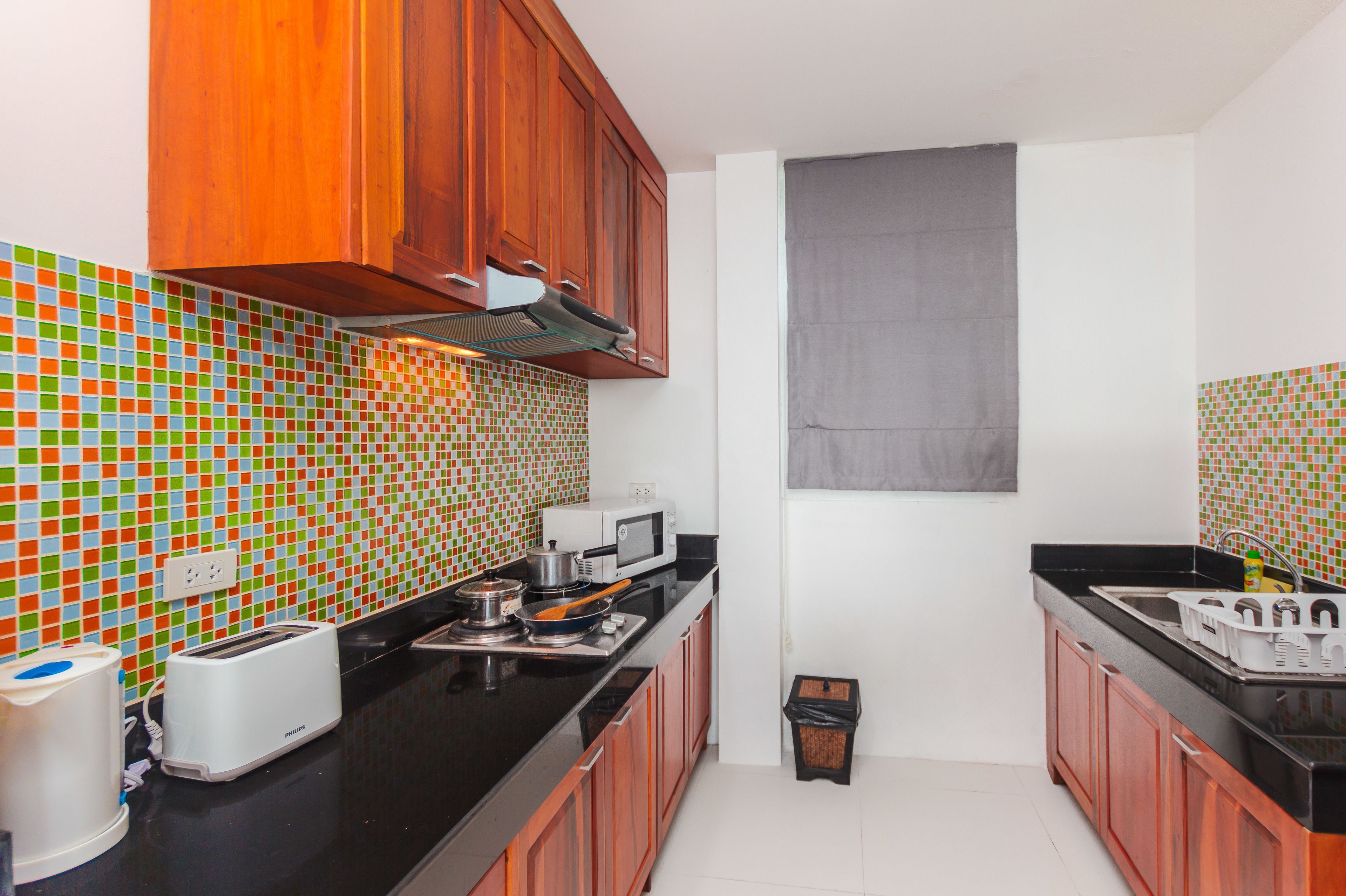 A kitchen with wooden cabinets, a microwave, a toaster, and a tiled backsplash.