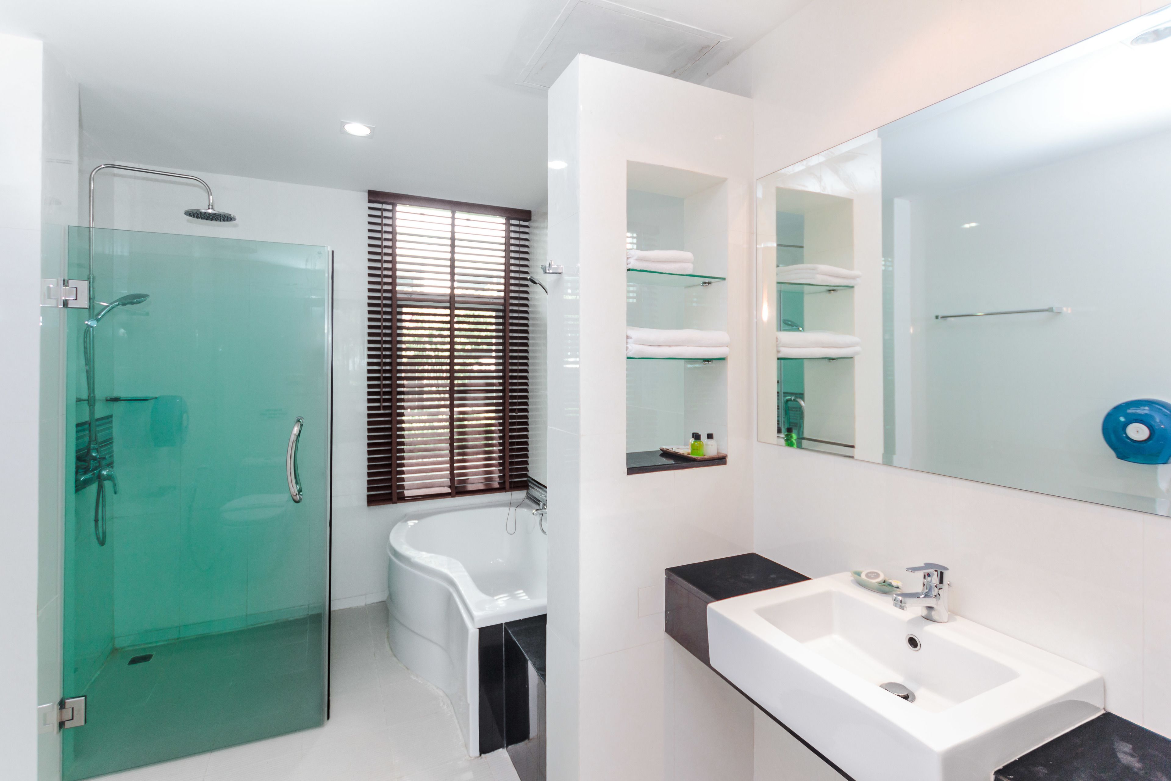 A modern bathroom with a glass-enclosed shower, a white bathtub, and a large mirror above the sink.