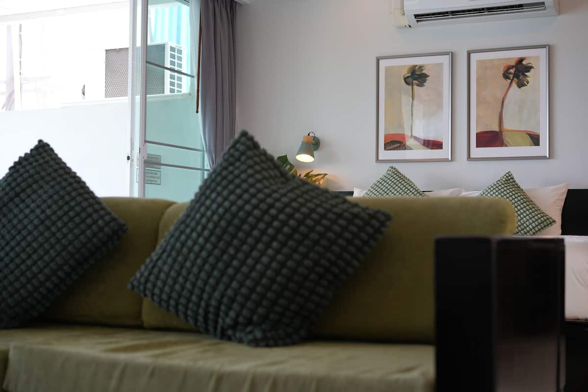 A living room with a sofa, pillows, a lamp, and two framed artworks on the wall.