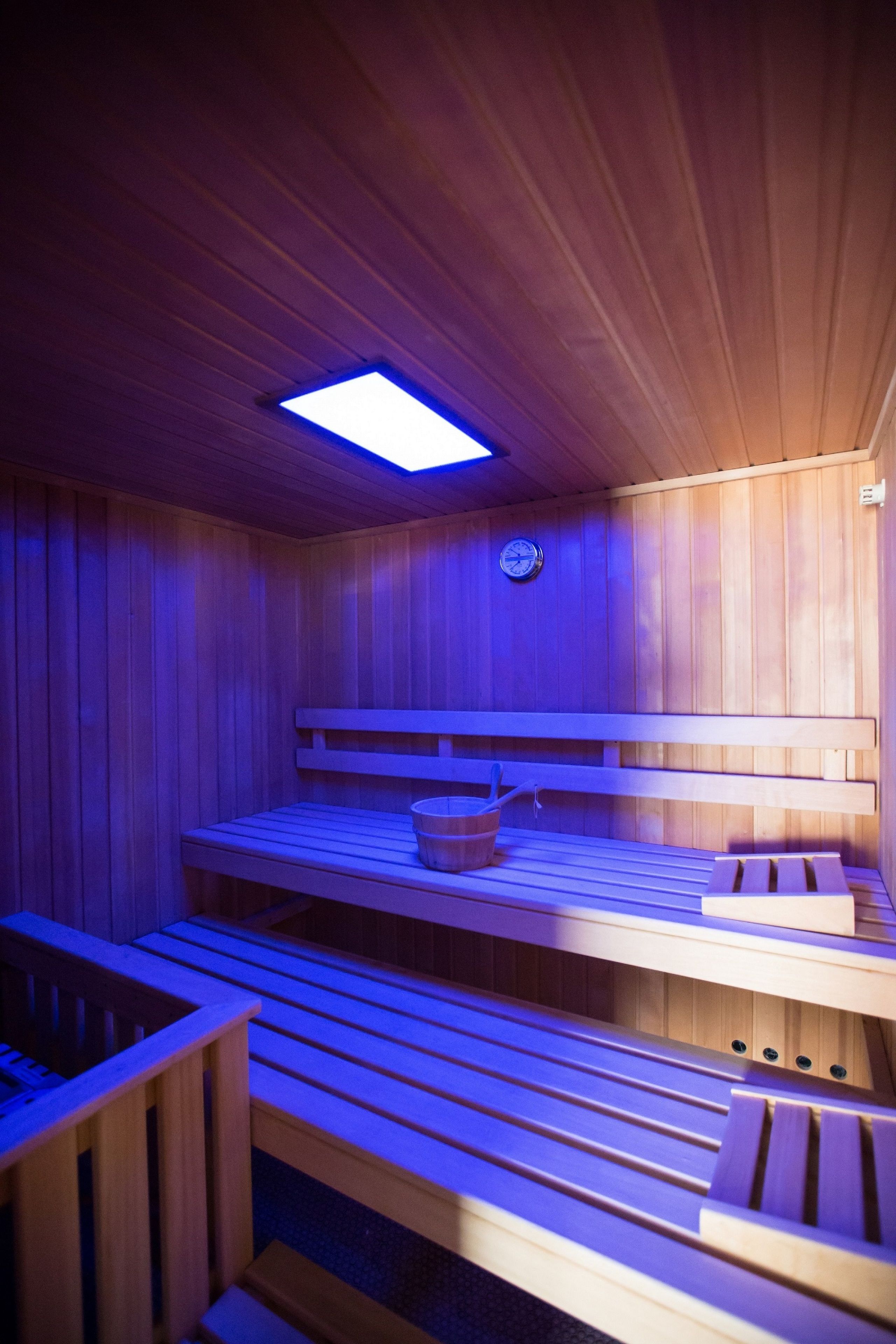 A wooden sauna with benches and a bucket.