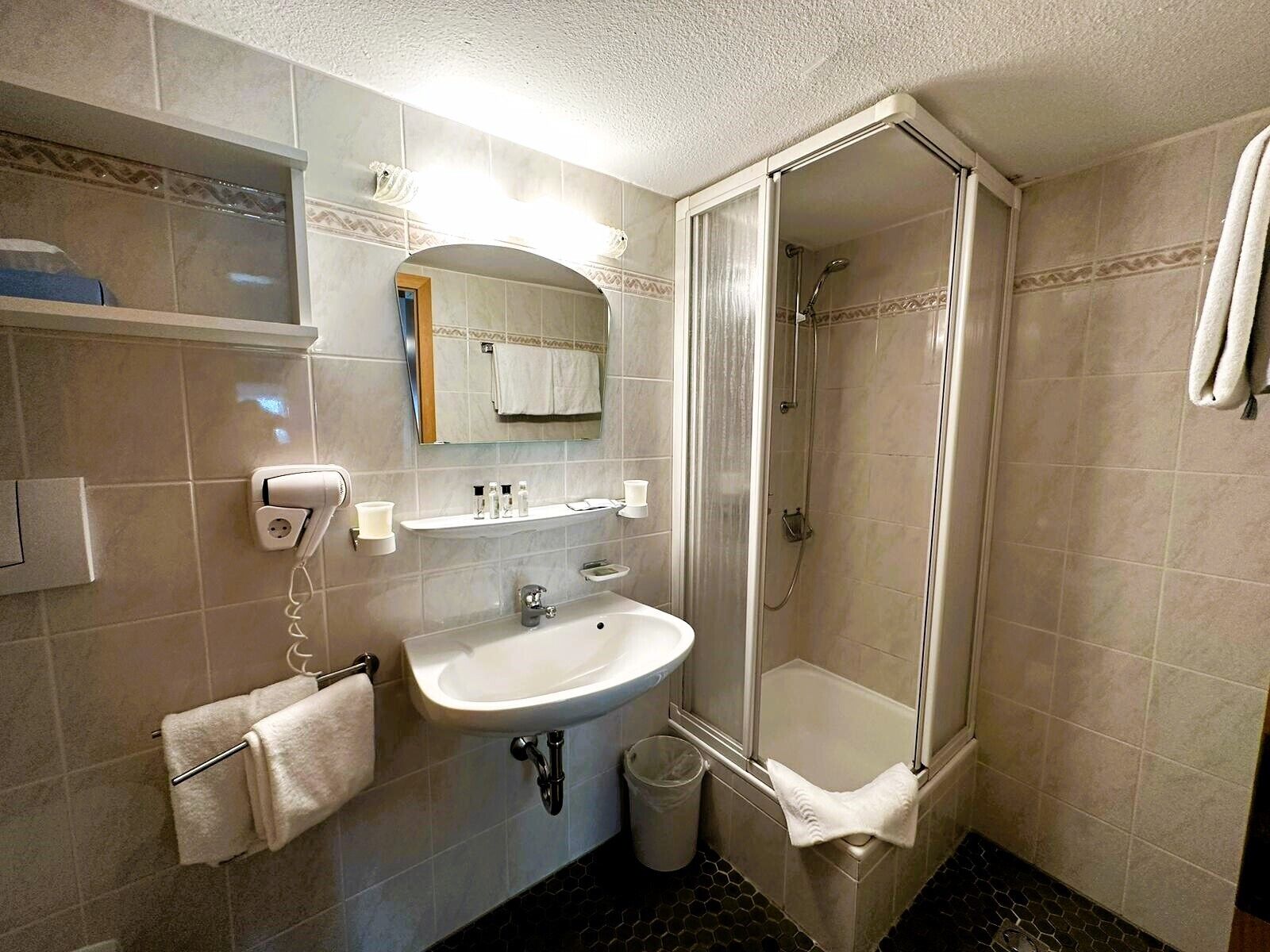 A bathroom with a sink, mirror, towel rack, and shower.