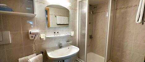 A bathroom with a sink, mirror, towel rack, and shower.
