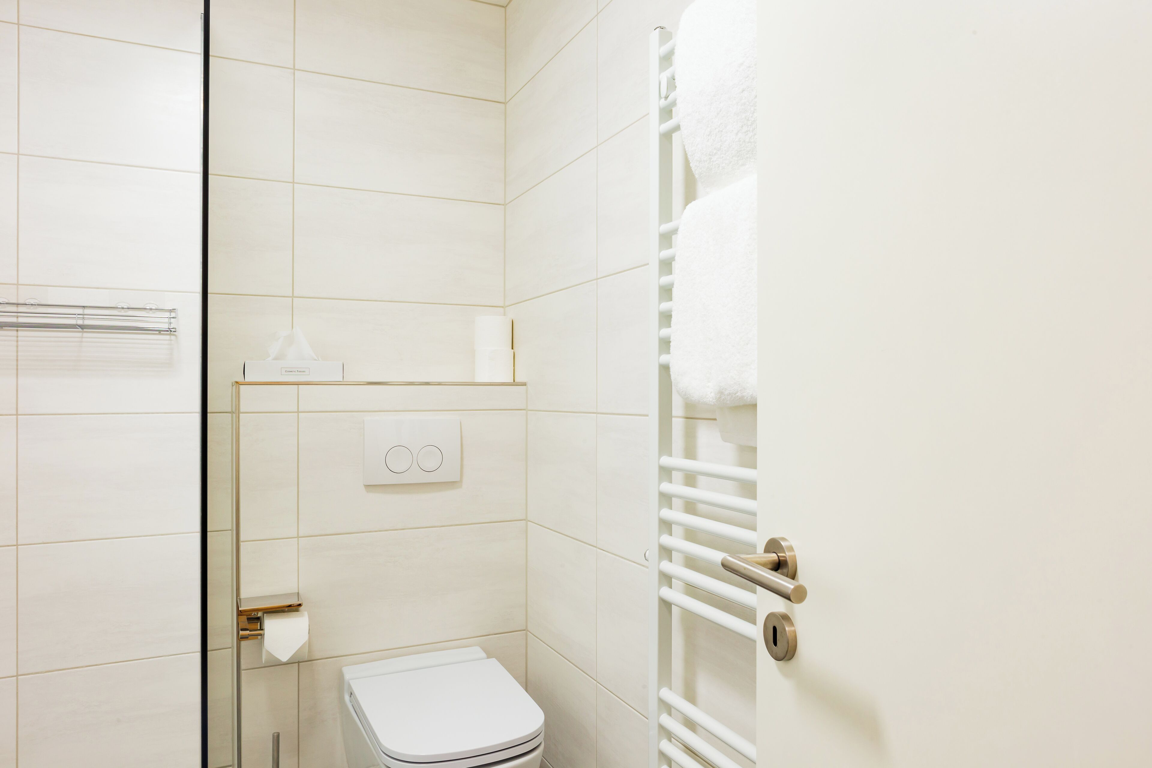 A bathroom with a toilet, towel rack, and a towel hanging on the rack.