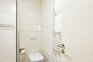 A bathroom with a toilet, towel rack, and a towel hanging on the rack.