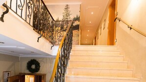 A grand staircase with marble steps and ornate black metal railings, leading to an upper floor. -  Hotel Sonnleiten (Reit im Winkl)
