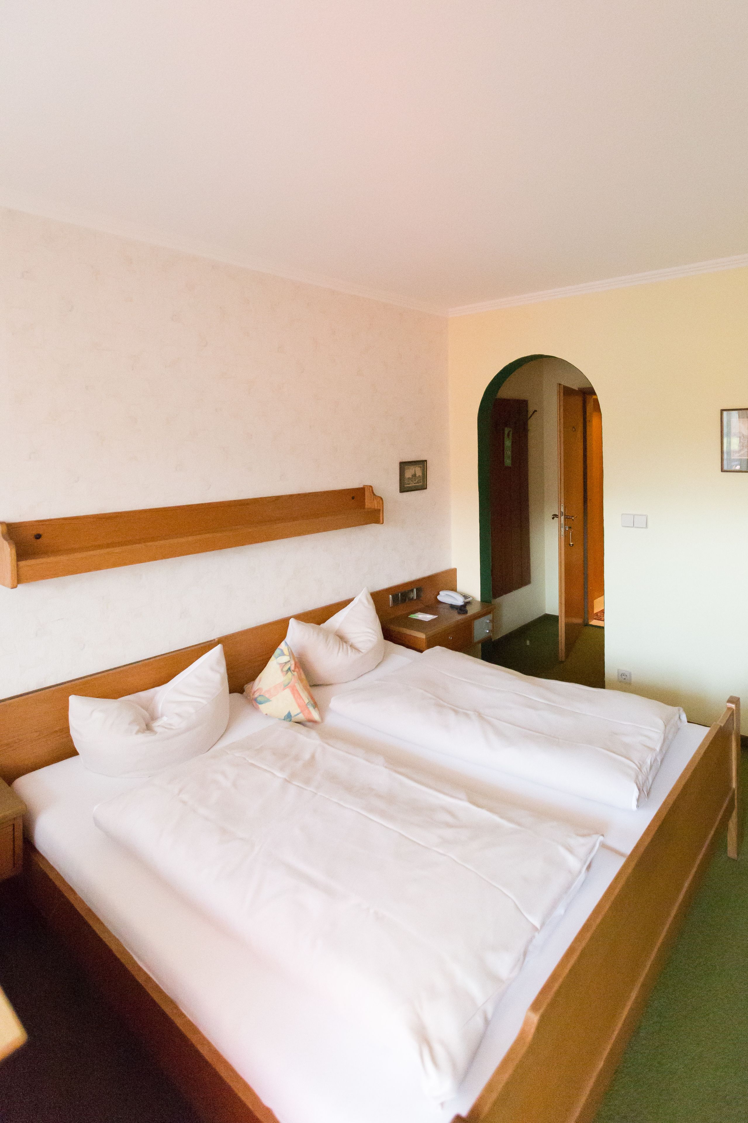 Una camera d'albergo con un letto grande, una testiera in legno, un comodino e uno specchio.