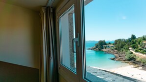 Ein Fenster mit Blick auf einen Strand und eine felsige Küste.