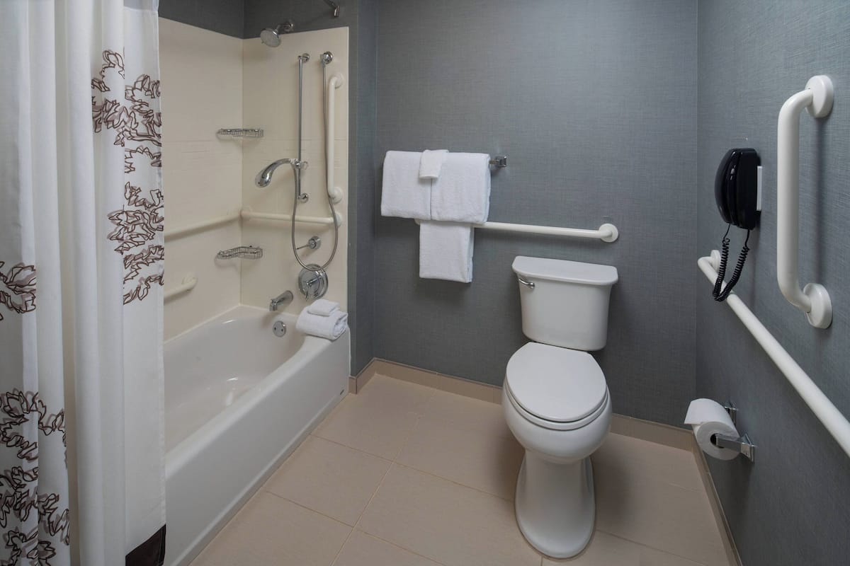 Une salle de bain équipée d’une baignoire, de toilettes et de barres d’appui.
