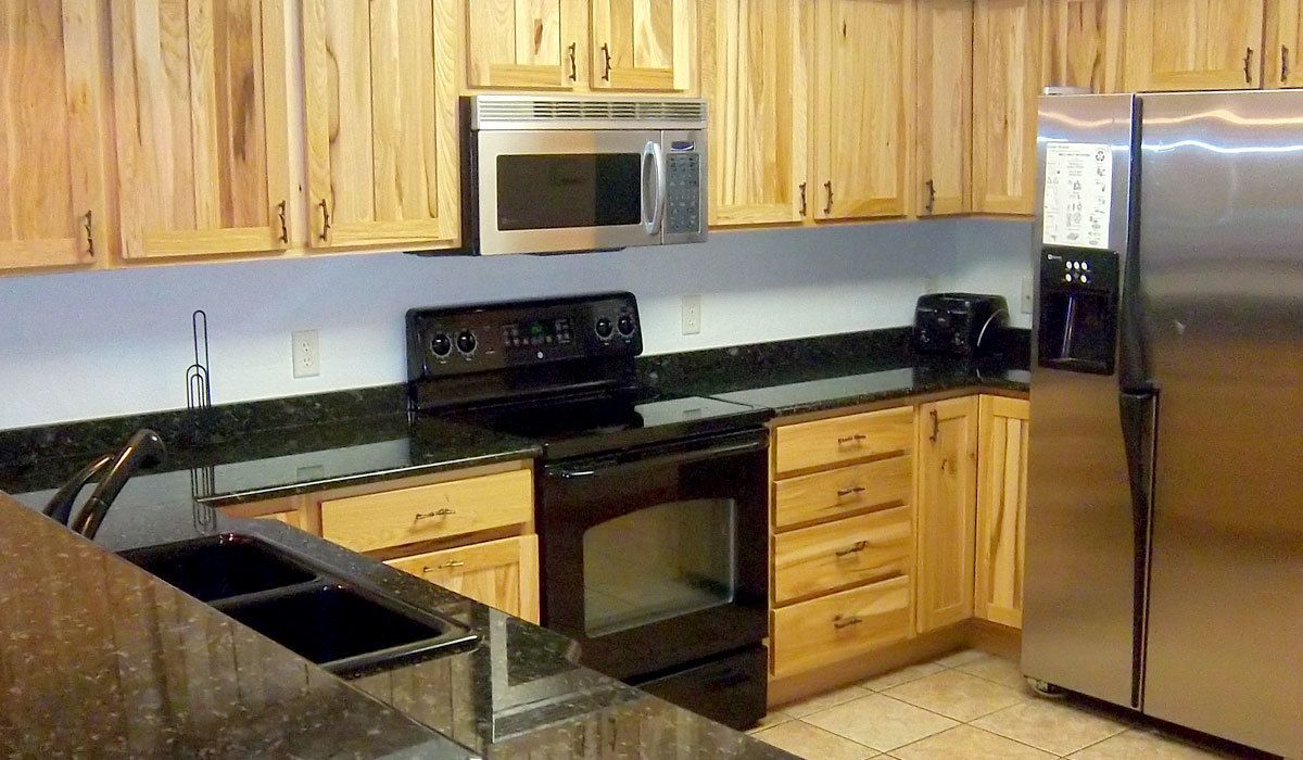 A kitchen with wooden cabinets, a stainless steel refrigerator, a microwave, a stove, and a dishwasher.