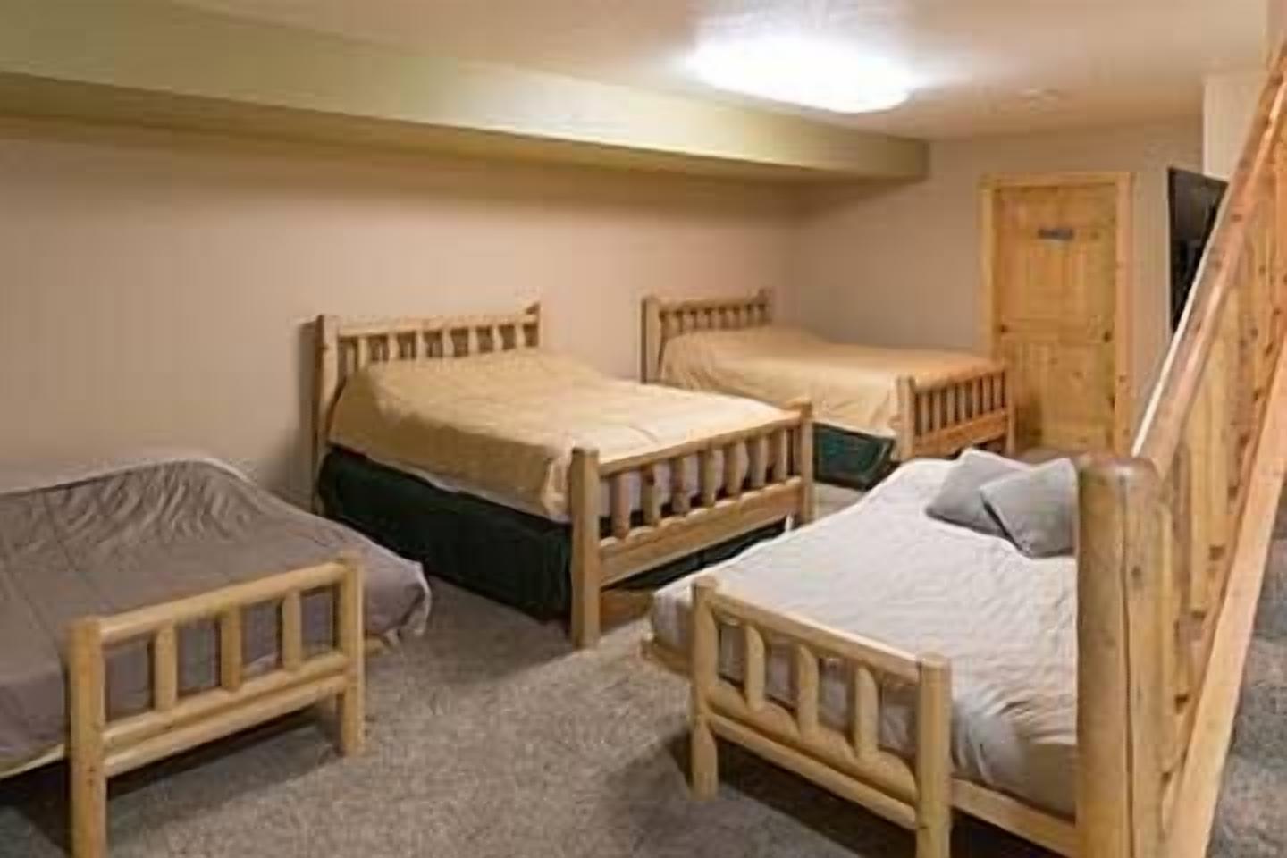 A room with three wooden beds, a wooden wardrobe, and a carpeted floor.