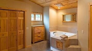 Un bagno con un mobile bagno in legno, una vasca e una piccola finestra.