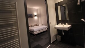 A modern bathroom with a white sink, dark tiles, and a mirror. - Hotel Vol de Nuit (Toulouse)