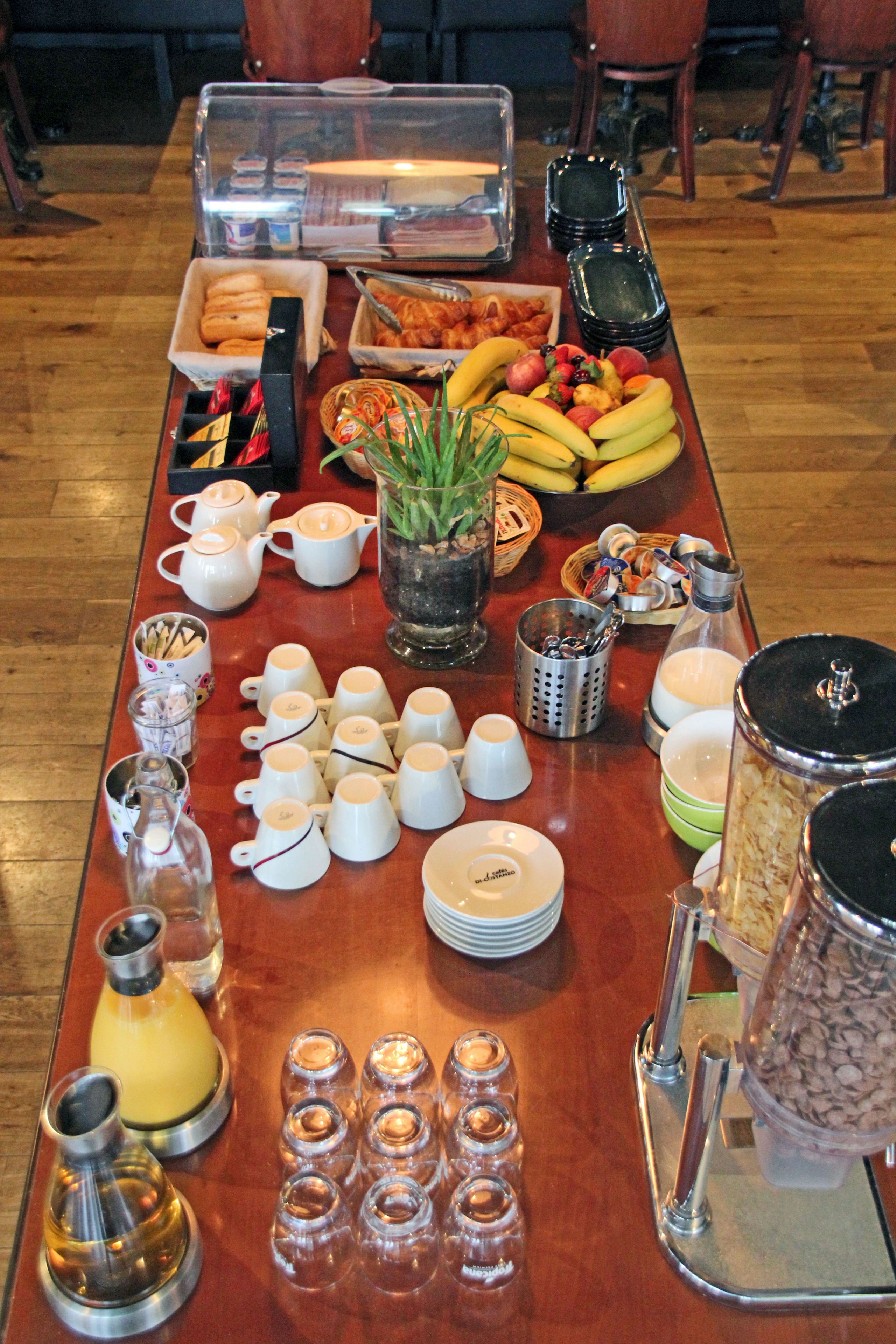 A breakfast buffet with various food items, cups, and condiments.