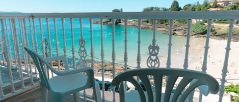 A balcony with white railings overlooking a beach.