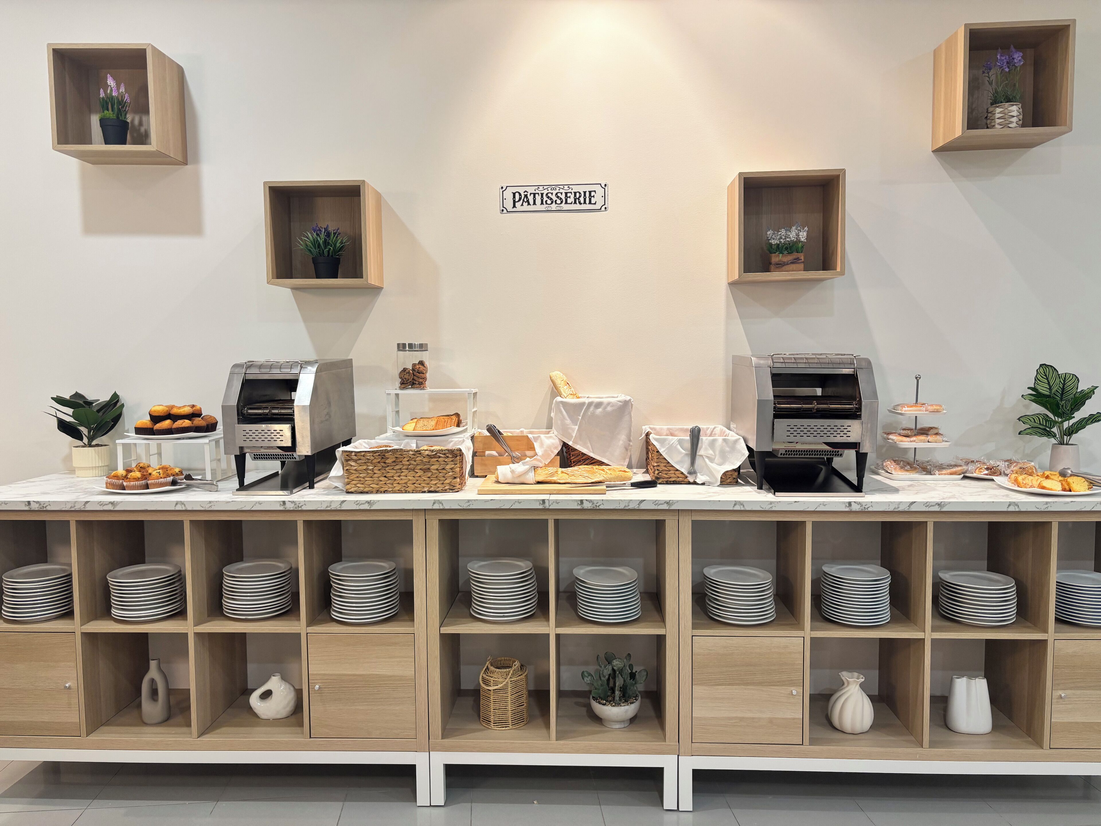 Montaje de bufé con diversos alimentos, una máquina de café y un letrero que dice 'Pâtisserie'.