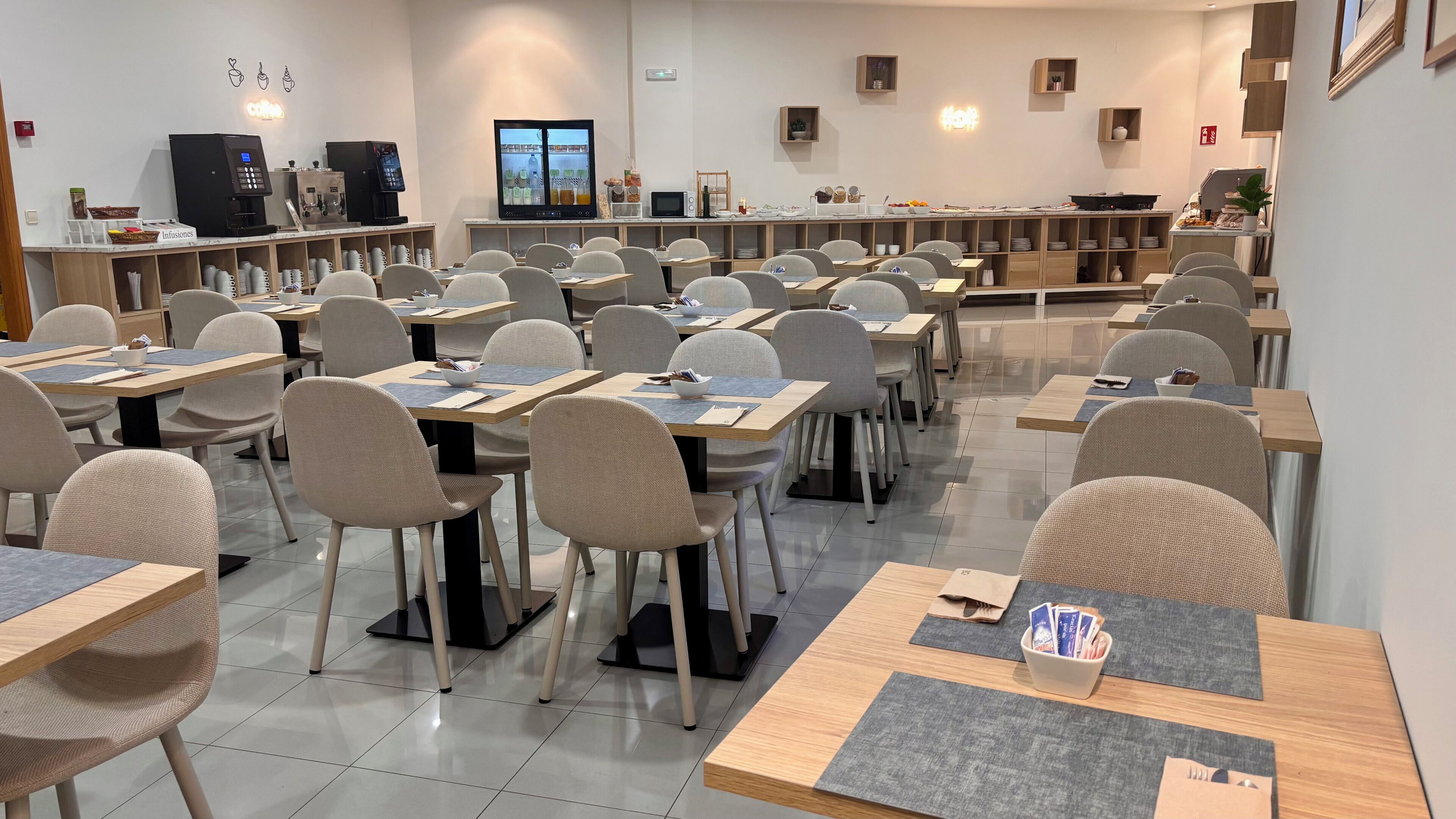 Une salle de conférence équipée de tables, de chaises, d’un coin café et d’un écran de télévision.