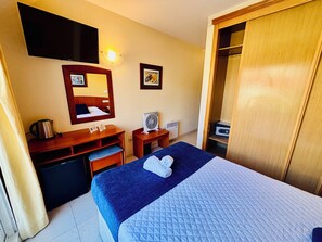 A hotel room with a bed, a desk, a chair, a television, a mirror, and a wardrobe. - Hotel Atalaya II (Sanxenxo)