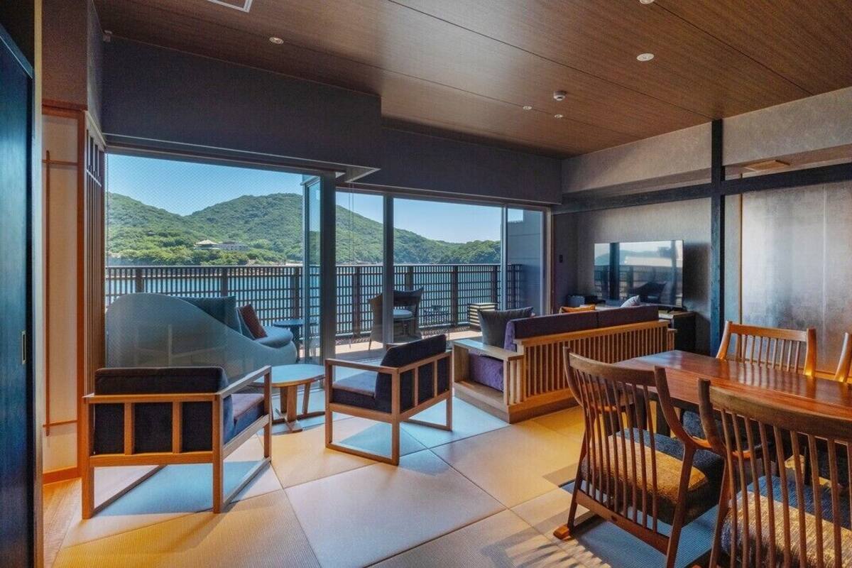 A modern interior with a dining area, seating, and large windows offering a view of a mountainous landscape.