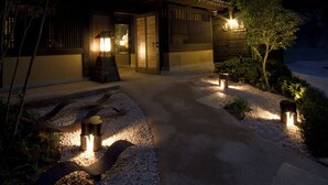 A traditional Japanese building with a wooden exterior, a tiled roof, and a gravel pathway leading to the entrance. - Migiwatei Ochi Kochi (Fukuyama)