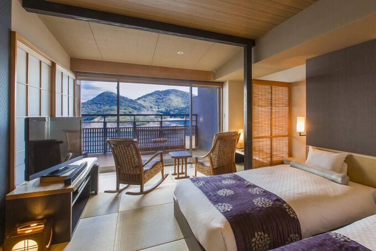 A hotel room with a balcony, a bed, a desk, and a chair.