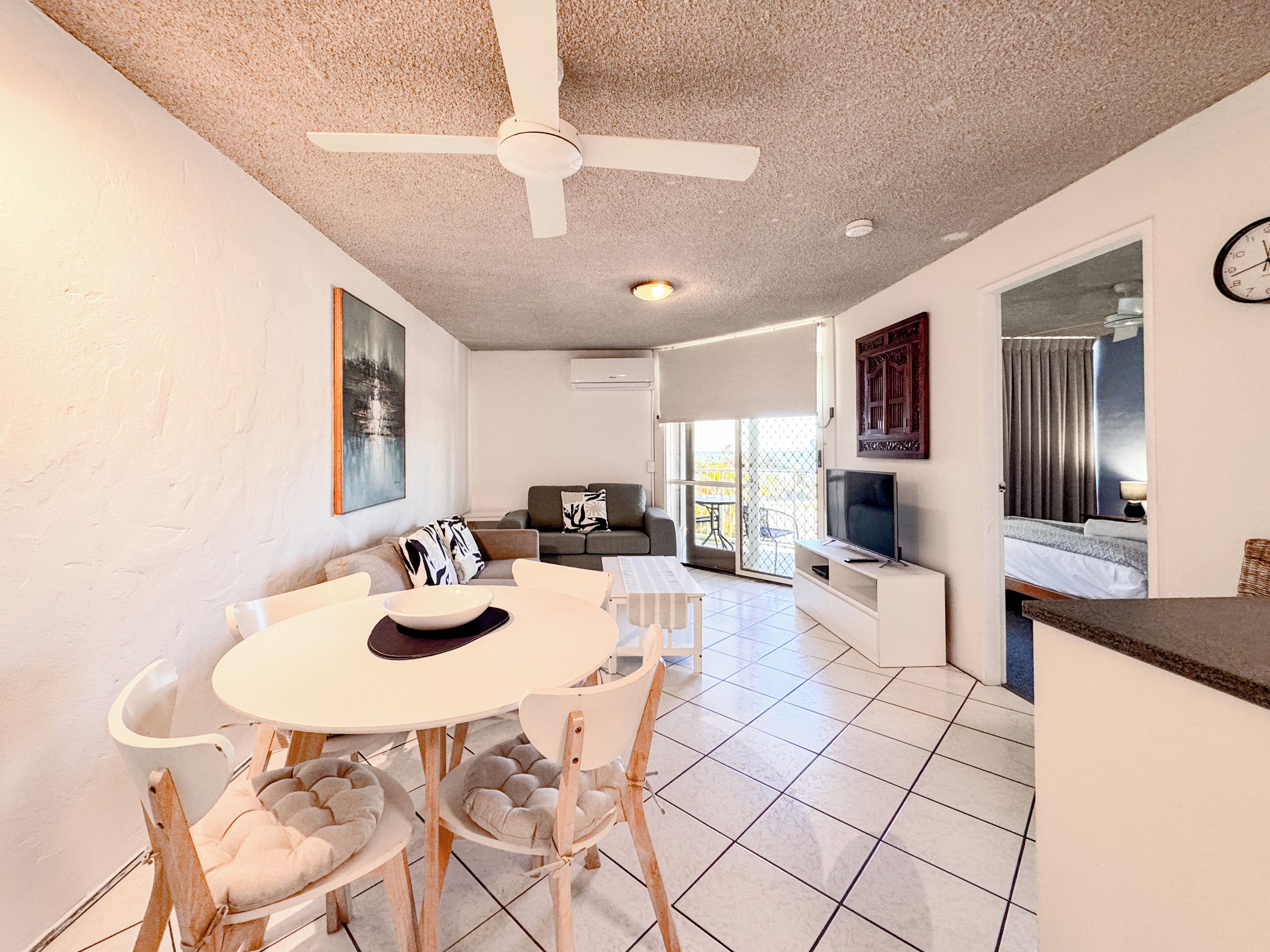 Un salon moderne comprenant un coin repas, un ventilateur de plafond et un téléviseur.
