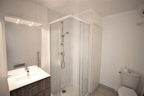 A modern bathroom with a glass-enclosed shower, a white sink, and a toilet. - Evancy Oye Plage (Oye-Plage)