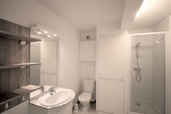 A modern bathroom with a marble sink, a toilet, and a glass-enclosed shower. - Evancy Oye Plage (Oye-Plage)
