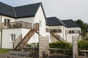 A row of white buildings with wooden balconies and stairs. - Evancy Oye Plage (Oye-Plage)