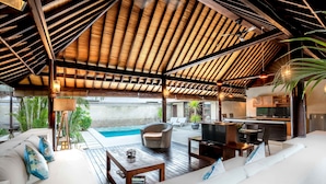 A spacious outdoor living area with a wooden deck, a pool, and a modern kitchen. - Gili Villas (Gili Trawangan)