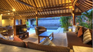 An outdoor living area with a TV, seating, and a covered patio. - Gili Villas (Gili Trawangan)