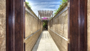 A narrow alleyway with a wooden pergola and a row of plants on one side. - Gili Villas (Gili Trawangan)